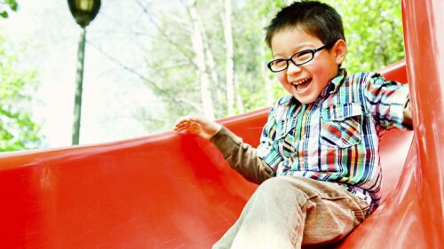 A little kid going down a slide at a park.