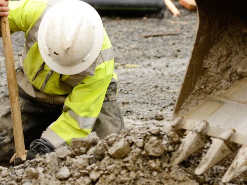 Construction worker digging dirt out with the help of crane