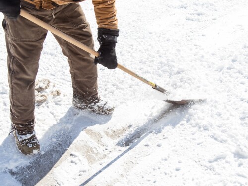 man scraping ice with shovel
