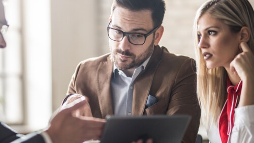 A man showing two other people something on a tablet.