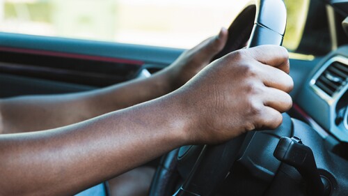Someone with their hands on their steering wheel.