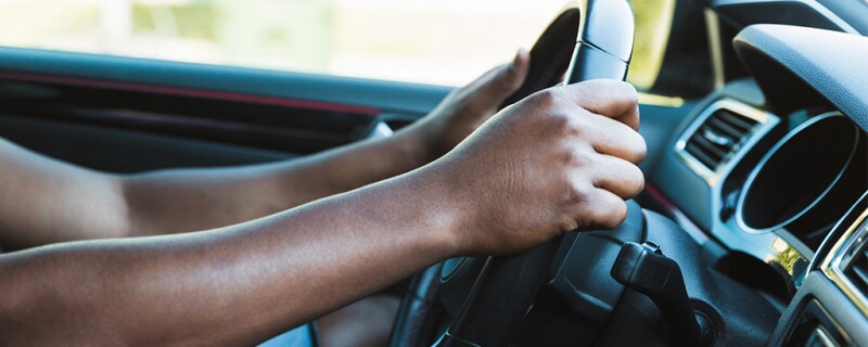 Someone with their hands on their steering wheel.