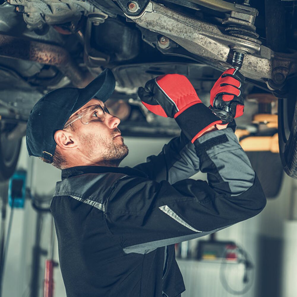 auto repair technician working on the underside of a vehicle