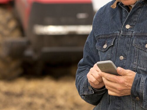 Farmer on his cellphone with his tractor behind him.