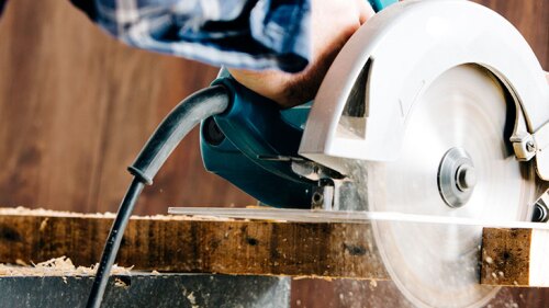 Someone using a table saw to cute a piece of wood.