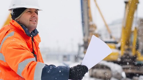 A worker outside in the cold holding a sheet of paper