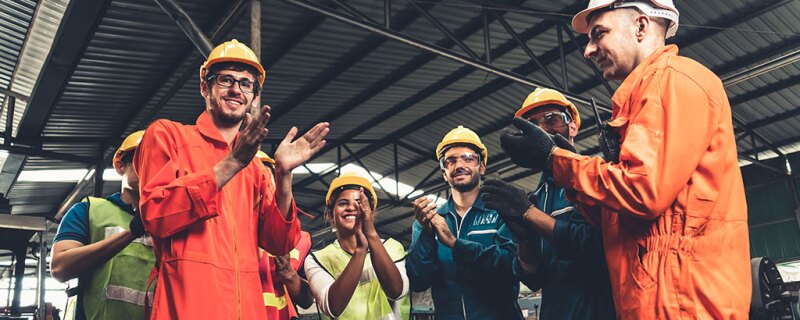 A group of factory workers clapping. 