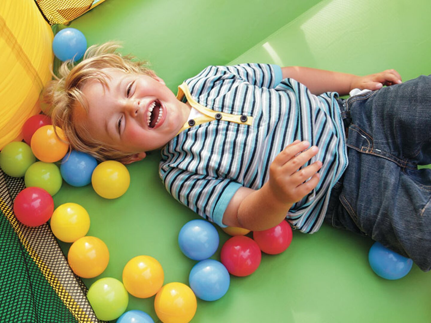 young boy playing in ball pit laughing