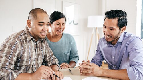 an insurance agent working with couple to review the insurance policy coverages.