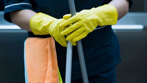 Housekeeper with gloves, towel, and a mop.