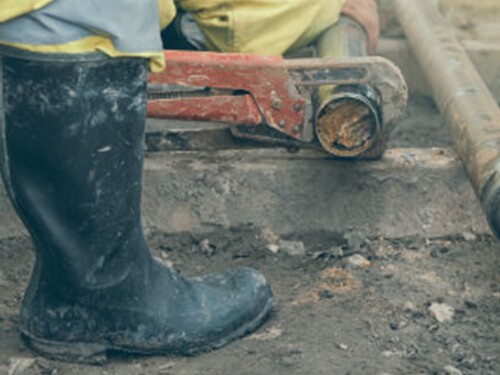 Someone in rain boots standing in mud.