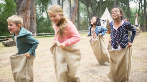 Four kids outside participating in a sack race.