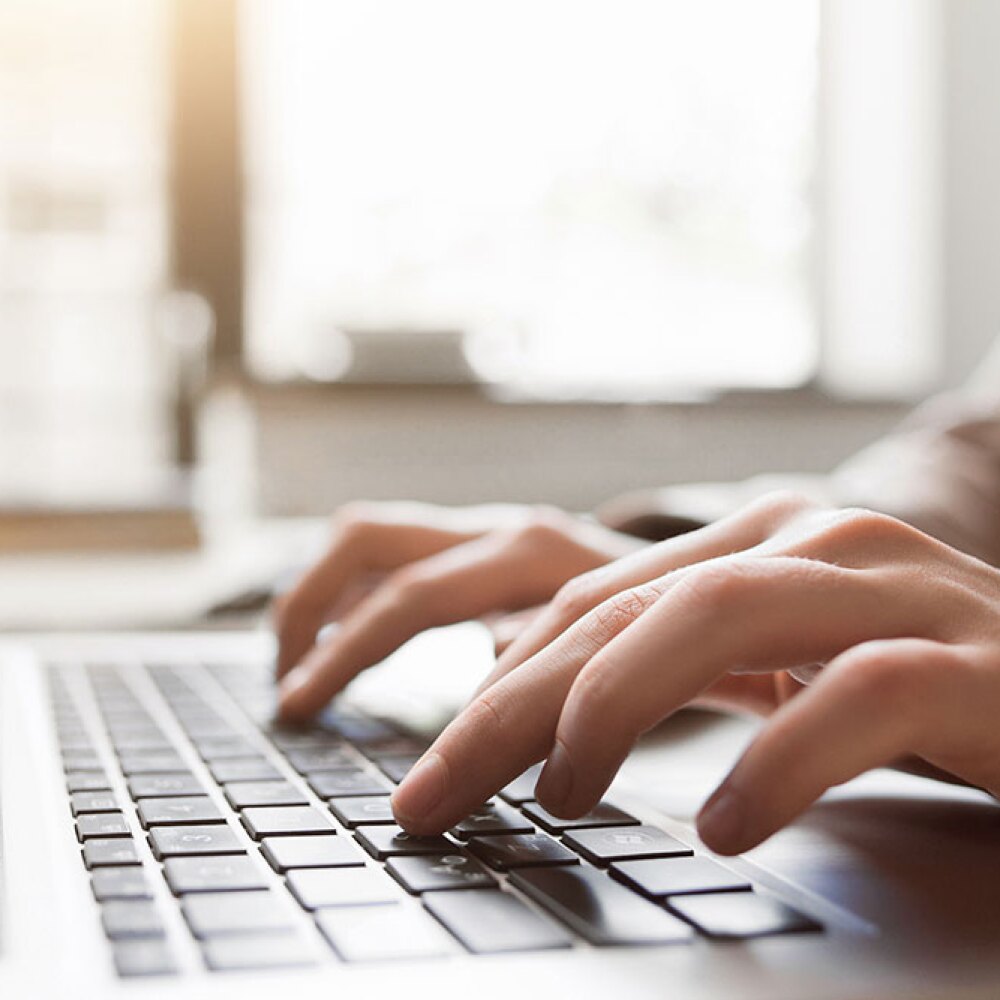 A person typing on their laptop keyboard. 