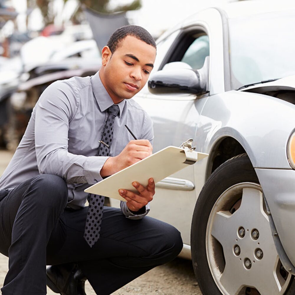 claims adjuster evaluating car damage