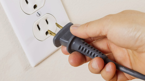 Someone plugging a cord into an outlet.
