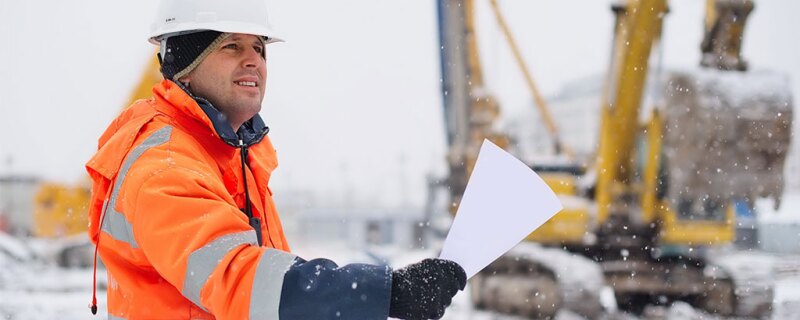 A worker outside in the cold holding a sheet of paper