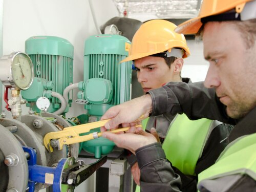 two plumbers working to fix industrial water fittings