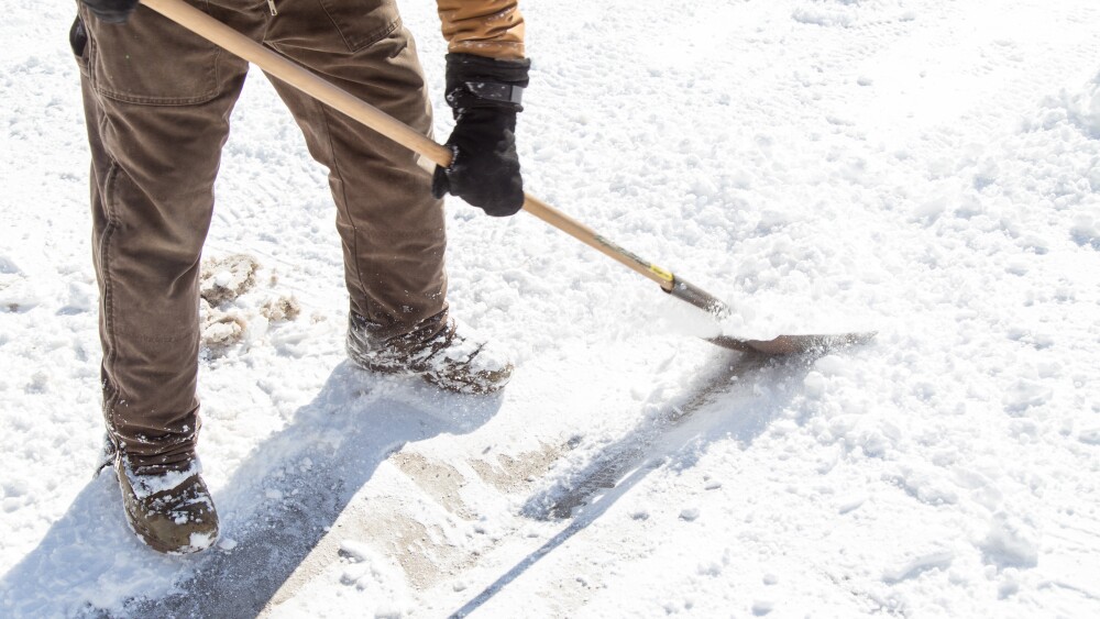 man scraping ice with shovel
