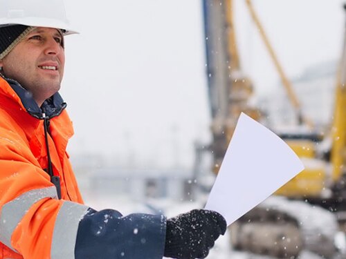 A worker outside in the cold holding a sheet of paper