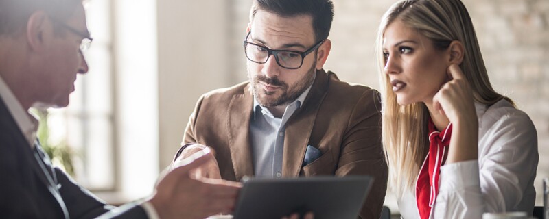 A man showing two other people something on a tablet. 