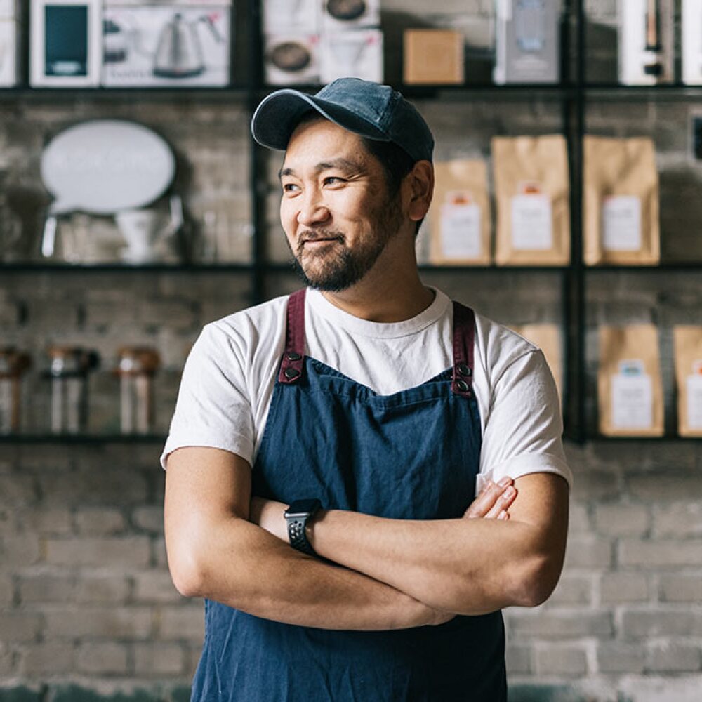 Japanese business owner standing at his coffee roastery smiling