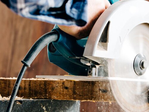 Someone using a table saw to cute a piece of wood.