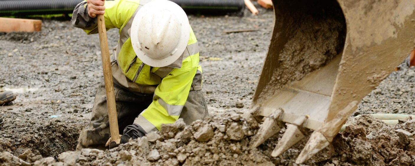 Construction worker digging dirt out with the help of crane