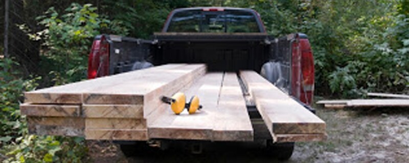 A truck with stacks of wood in the bed of the truck.