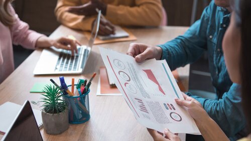 four people working together, taking notes, and looking at data.