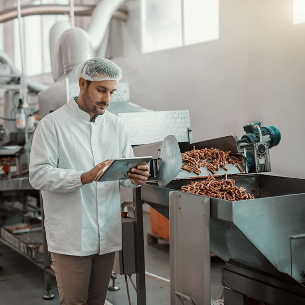 production line workers in food manufacturing facility monitoring the product using tablets