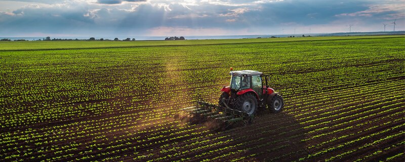 A farmer in his tractor cultivating his farming land