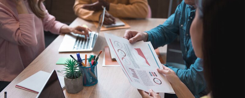 four people working together, taking notes, and looking at data.