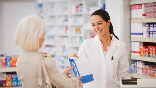 Pharmacist handing customer prescription in drug store