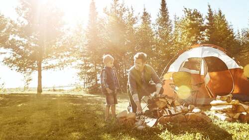Father and son camping and building a fire together.