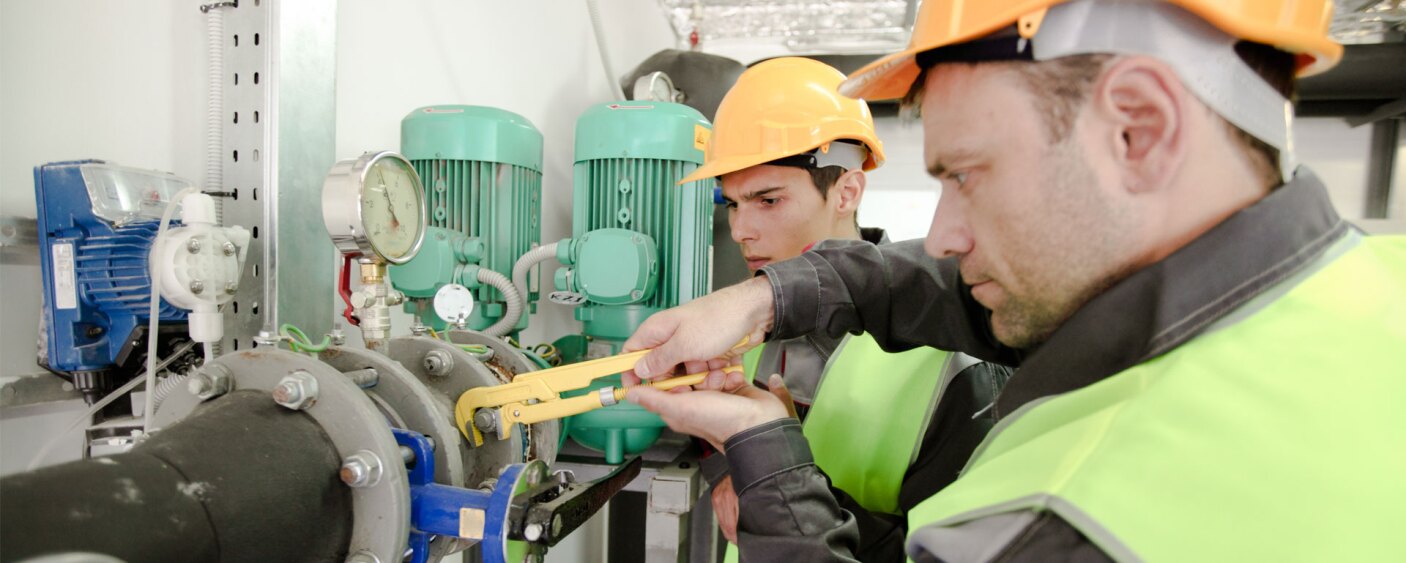 two plumbers working to fix industrial water fittings